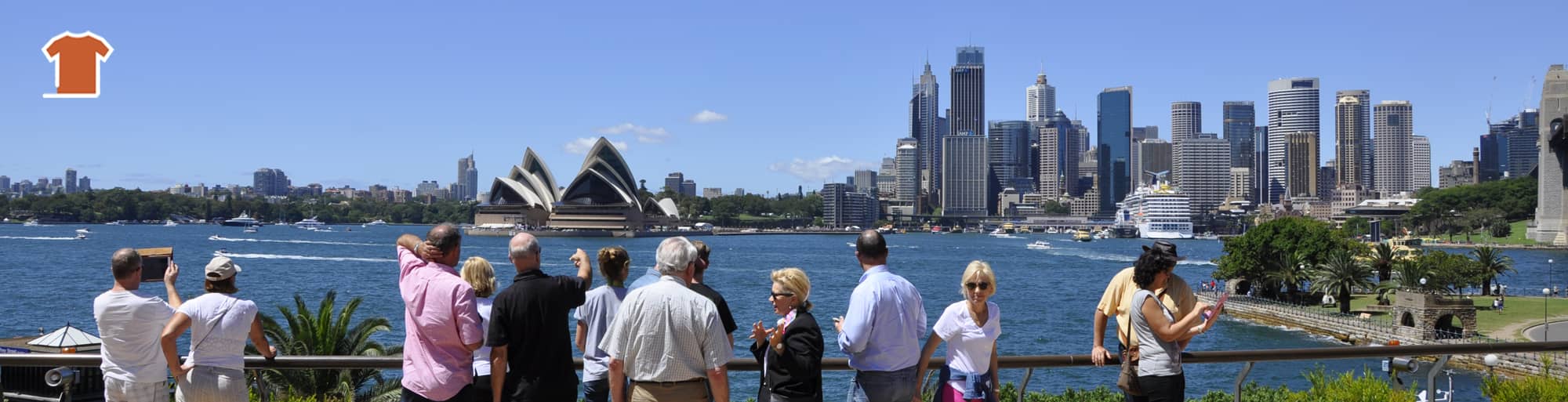 A Sydney sightseeing bus has stopped at Mrs Macquarie's Point, where tourists are taking pictures of the Sydney Opera House and Sydney Harbour Bridge in the background.