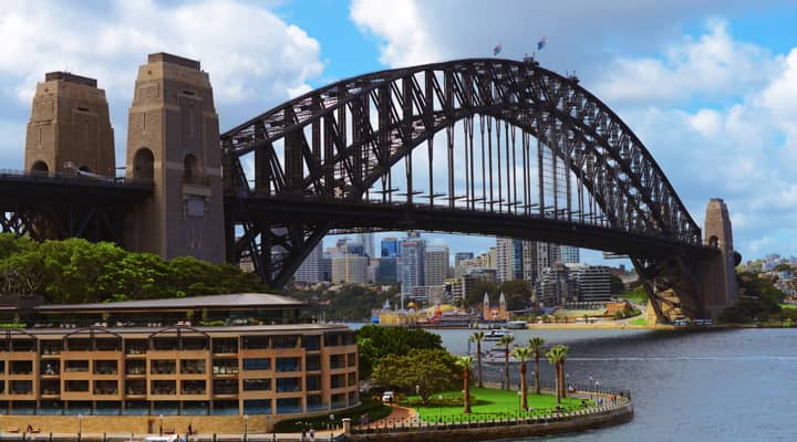 A group of tourists on a Sydney sightseeing bus tour enjoy the views of the city skyline from the lookout next to Kincoppal School in Vaucluse, Sydney, Australia. The tourists are taking pictures of the city, which is in the distance.