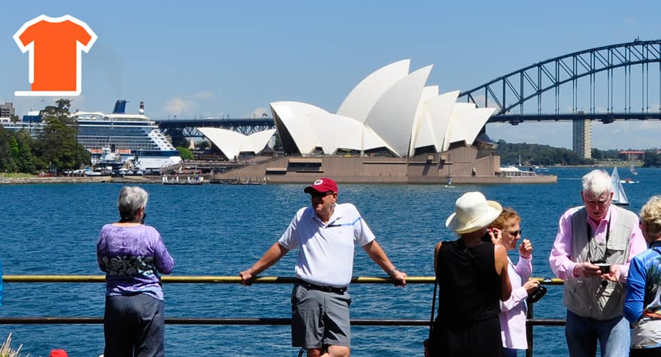 Sydney sightseeing bus tour stopped at Mrs.Macquaries Point. Travelers are taking pictures with the Sydney Opera House and Sydney Harbour Bridge at the background.