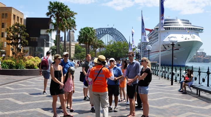 Tourists at the West Circular Quay listening to a tour guide in orange free tours uniform.